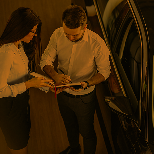 Homem e mulher lado a lado analisando papéis. Ambos usam camisa social branca. Ilustração do texto sobre seguro de locação de carros.